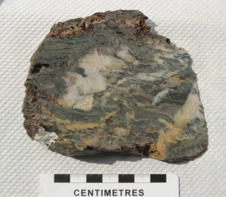 Image couleur d’une roche grise avec veines de couleur or, blanc et orange