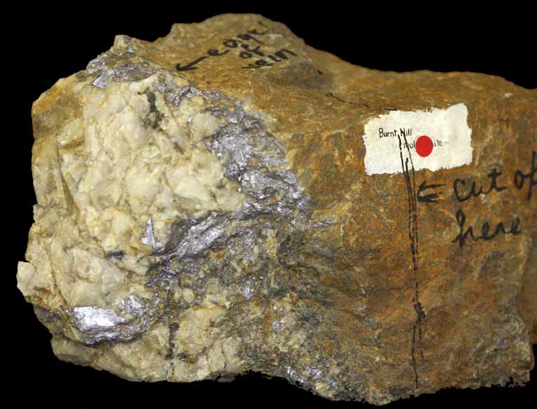 Image couleur d’une roche brune avec grandes sections de roche métallique blanche et grise