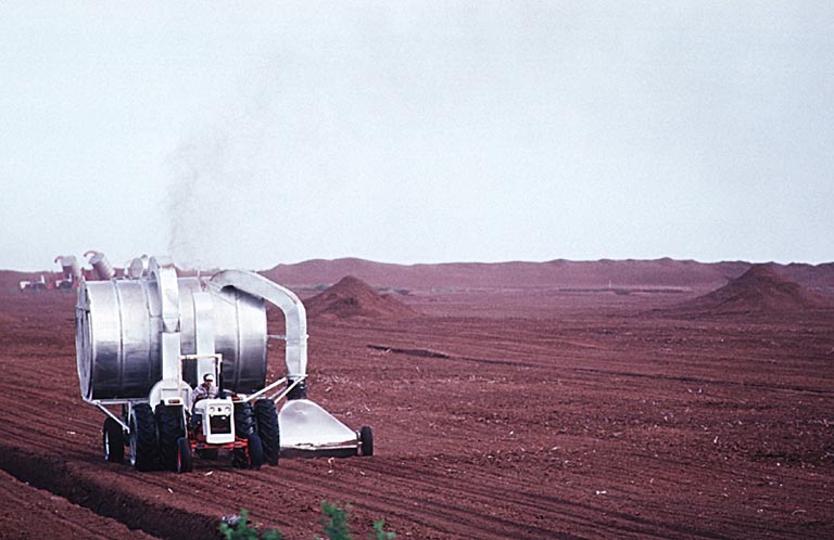 Photographie couleur d’un homme au volant d’un tracteur dans un champ brun
