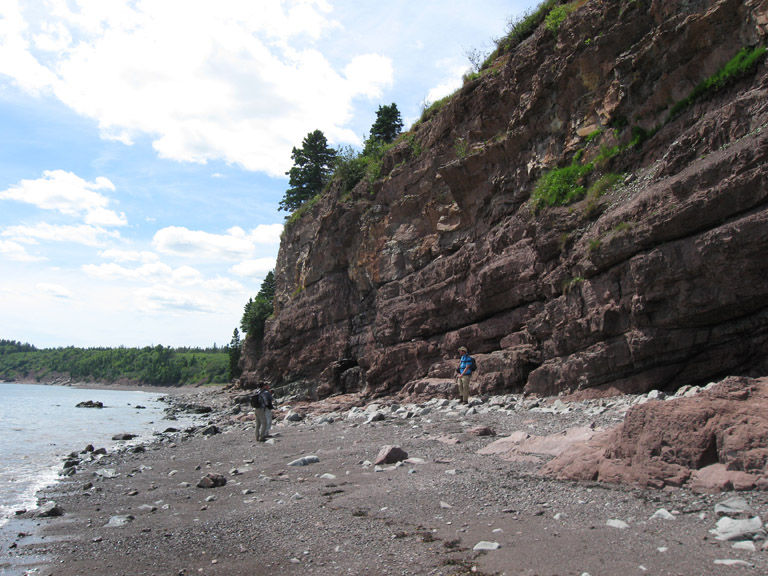 Photographie couleur d’un homme debout devant des rochers roses